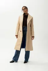 Trench largo de cuero color beige con forro azul, cuello clásico, cierre frontal con botones y bordado de las "S" en el frente.