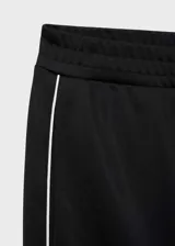 Pantalón de corte recto y tiro medio, color negro con detalle de raya lateral blanca en contraste. Cuenta con cintura elástica y bolsillos laterales.