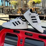 Championes urbanos adidas Forum Low CL, color blanco con las icónicas tres tiras laterales en negro. Presentan un diseño de caña baja con cierre de cordones, suela de goma resistente y el logo del trébol de adidas en la lengüeta y el lateral.