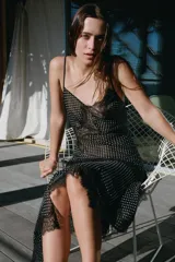 Vestido midi de tirantes finos con escote en pico, confeccionado en viscosa con estampado de lunares. Presenta aplicaciones de encaje en el escote y en la falda, con un bajo de acabado asimétrico.