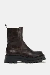 Botín de estilo urbano con efecto desgastado, confeccionado con suela de plataforma dentada y puntera redonda. Cuenta con un diseño tipo pull-on y tirador trasero para facilitar el calce.