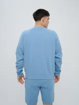 Buzo de felpa bordó, estilo relaxed, con cuello redondo y mangas raglán. Presenta puños y dobladillo acanalados, y una pequeña etiqueta con el logo de Umbro en el lateral inferior.