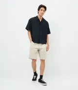 Bermuda masculina de corte slim confeccionada en sarga de algodón. Presenta un diseño de sastrería con cintura con trabillas, cierre tradicional y bolsillos laterales y traseros.