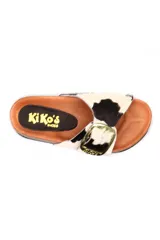 Sandalia tipo zueco con capellada de cuero con pelo estampado animal print de vaca en blanco y negro. Presenta una hebilla metálica dorada grande en el empeine, plantilla anatómica de corcho y suela de goma negra.