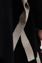 Polera negra de cuello alto, corte oversized y mangas largas con detalle de franjas color crema en los hombros.