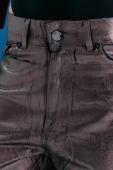 Pantalón de jean estilo oversize de tiro medio-bajo, confeccionado en denim 100% algodón. Presenta un acabado metalizado en tono peltre con efecto lavado violeta, logrando un brillo irregular y profundo. Incluye avíos metálicos personalizados y badana de PU en la parte posterior.