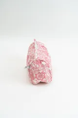 Neceser de tela acolchada con estampado floral en tonos rosados sobre fondo blanco, con cierre superior y estructura rectangular.