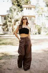 Pantalón de tiro alto confeccionado en cuero sintético, de corte amplio y pierna ancha con costura horizontal a media altura.