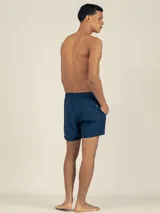 Short de baño azul marino con cintura elástica y cordón blanco con detalles en cobre. Presenta un parche bordado con una flor blanca y roja en la pierna izquierda y un parche con logo en la pierna derecha.