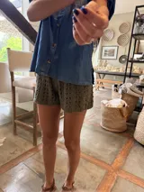 Short de tejido de punto crochet color beige, de cintura elástica y diseño holgado, con detalle de etiqueta de cuero de la marca Antonia Wool Wear en la cintura.