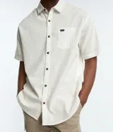 Camisa de corte relajado para hombre, confeccionada en una mezcla de cáñamo y algodón. Presenta cuello inglés, manga corta, cierre frontal con botones y un bolsillo en el pecho con una pequeña etiqueta aplicada.