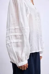 Camisa blanca de mangas largas con apliques de encaje en los puños y en los hombros.