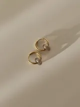 Aros de acero quirúrgico dorado con dije colgante en forma de piedra natural grisácea.