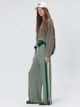 Pantalón de punto jacquard con diseño geométrico texturizado, de corte holgado y pierna ancha. Presenta tiro medio, cintura elástica con cordón ajustable y aberturas laterales en el ruedo.