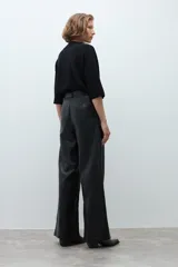 Pantalón de tiro alto confeccionado en eco cuero negro, con diseño de pierna ancha y pinzas frontales.