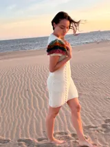 Vestido midi de punto color marfil, confeccionado en lana merino, con mangas cortas decoradas con flecos mullidos de varios colores y trenzas verticales al frente.