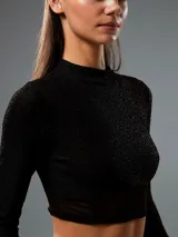 Top negro con cuello alto, mangas largas de tul y corte crop.