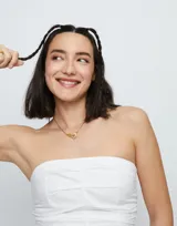 Collar dorado con dije de mosquetón entrelazado.