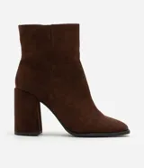 Bota de caña corta con acabado aterciopelado, punta cuadrada y taco bloque alto. Presenta un diseño minimalista y estructurado con cierre lateral.