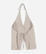 Chaleco color beige con escote halter, corte al cuerpo y cierre frontal con botones. Presenta un bolsillo de ojal en el frente.