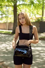 Bolso bandolera negro de cuero, con correa ajustable y desmontable. Tiene un compartimento principal con cierre y dos bolsillos frontales con cierre.