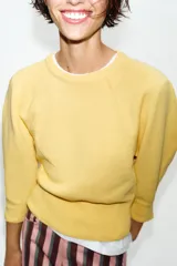 Jersey de punto color amarillo claro, con cuello redondo y mangas abullonadas.