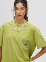 Remera verde agua con cuello redondo y manga corta, con un pequeño estampado de una estrella en el pecho. Corte holgado y cuadrado.