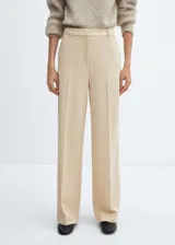 Pantalon de vestir de corte wideleg y tiro bajo, en color beige. Presenta trabillas para cinturón, bolsillos laterales y cierre oculto con botón, gancho y cremallera.
