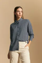 Camisa de manga larga con cuello camisero y cierre frontal de botones. Presenta un estampado geométrico pequeño en tonos azul marino y blanco, con una silueta relajada y tejido liviano.