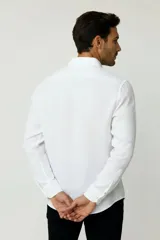 Camisa blanca de algodón, de diseño holgado y manga larga, con cuello camisero y cierre frontal de botones.