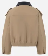 Campera Comfort de poliéster color camel, con cuello de poliuretano en contraste color marrón oscuro, cierre frontal y bolsillos con solapa y botones. Presenta martingalas en los hombros y elástico en la cintura.