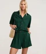 Short runner de viscolino, con cintura elástica, botón decorativo y bolsillos laterales. Presenta un corte evasé holgado con bajo redondeado.