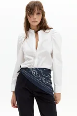 Camisa blanca de algodón con cuello mao, hombros abullonados y mangas largas. Cierre frontal con botones de nácar.