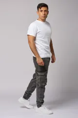 Pantalón jean gris oscuro de corte jogger con bolsillos cargo laterales y puños elásticos en los tobillos.