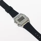 Reloj digital plateado con correa de caucho negra.