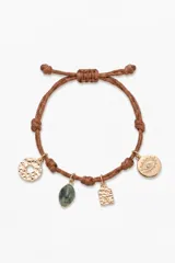 Pulsera de cordón marrón ajustable con nudos decorativos y cuatro dijes colgantes: un disco texturizado, una piedra verde, una placa rectangular texturizada y un dije circular con diseño de ojo y piedra central.