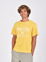 Remera de algodón color mostaza con estampa frontal blanca alusiva a un torneo de tenis.