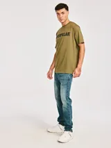 Remera de manga corta color verde oliva con cuello redondo y logo de la marca Caterpillar estampado en negro en el pecho.