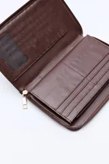 Billetera capitoneada en símil cuero color negro, con pespuntes en diagonal y cierre perimetral. Cuenta con un logo metálico dorado en el frente.