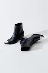 Bota estilo texana de cuero negro con puntera metálica plateada, taco cuadrado y cierre lateral interno.