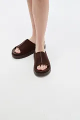 Sandalias de gamuza marrón, diseño abierto con tira ancha en el empeine y suela plana de goma.
