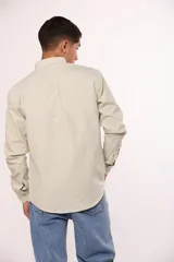 Camisa de manga larga en color gris, confeccionada en algodón, con cuello abotonado y cierre frontal de botones.