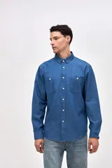 Camisa de corte regular fit confeccionada en algodón, con cuello solapa clásico, cierre frontal de botones y dos bolsillos frontales en el pecho.