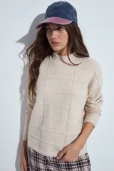Sweater de punto gris con cuello a la base y diseño de trama geométrica en relieve. Presenta un calce relajado con mangas largas y puños tejidos.