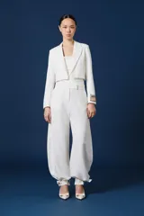 Saco corto tipo blazer color negro, de corte entallado y manga larga. Presenta un detalle distintivo en el puño izquierdo con una banda en tono dorado que incluye la inscripción 'ANTOLIN'.