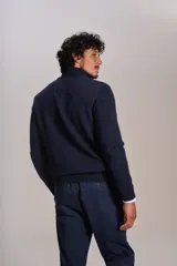 Cardigan de punto color azul marino, con cuello alto, cierre frontal completo y puños acanalados. Presenta el logo de la marca bordado en el pecho.