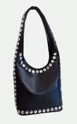 Cartera tipo hobo de cuero sintético negro, con diseño de tachas metálicas plateadas circulares que bordean la abertura y la base.