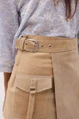 Minifalda beige de cuero con diseño cruzado, cinturón con hebilla metálica y bolsillo tipo cargo con solapa.
