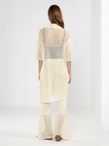 Camisa larga negra de punto calado con cuello camisero, manga tres cuartos y cierre frontal con botones.