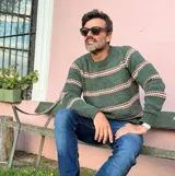 Sweater de punto con cuello redondo, diseño de rayas horizontales en tonos verde, blanco y marrón, de manga larga y calce clásico.